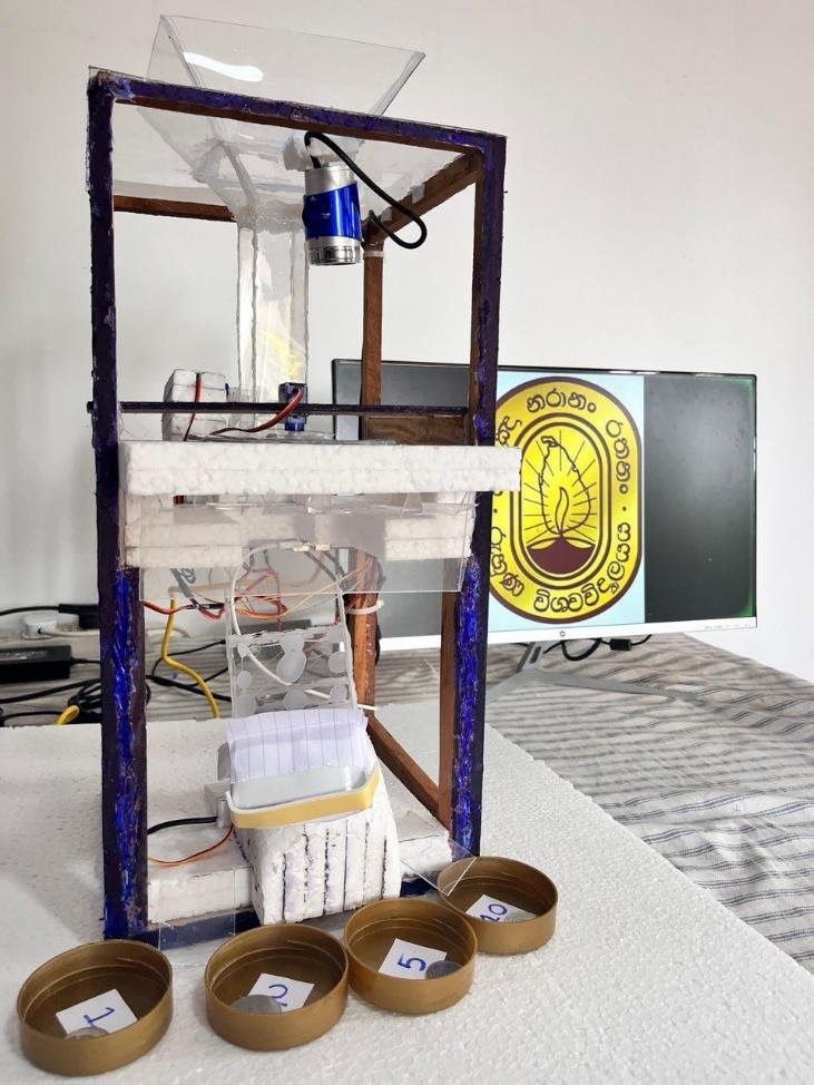 Front view of the fabricated coin sorter with its vertical frame, coin tube, two cameras, and four collection bins