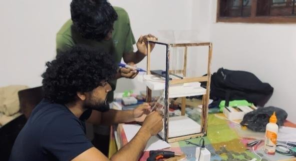 Team members assembling the coin sorter on a workbench